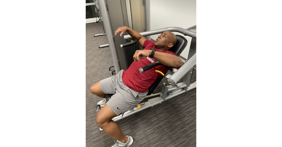 Eric sitting on a shoulder press machine unmotivated